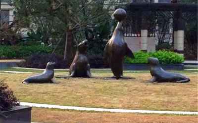 公園草坪上擺放的貪玩的玻璃鋼仿銅海豹雕塑